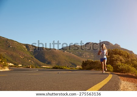 Young woman running on an empty road