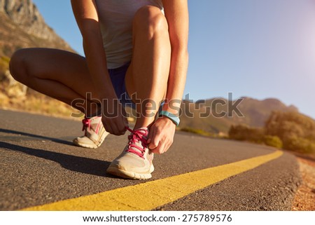 Cropped shot of female jogger doing up her shoe lace