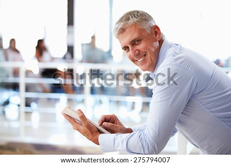 Portrait of middle aged man in office using tablet