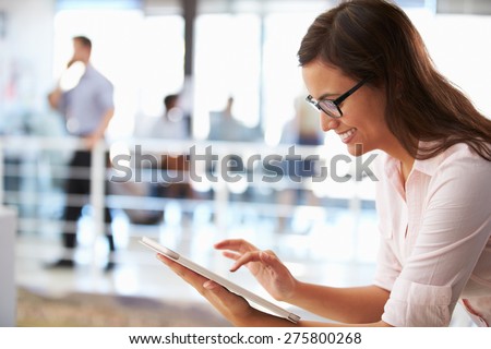 Portrait of smiling woman in office with tablet, side view