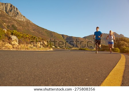 Man and woman running together on an empty road
