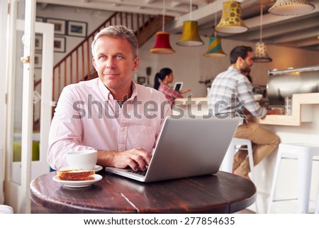 Middle aged man using laptop in a cafe