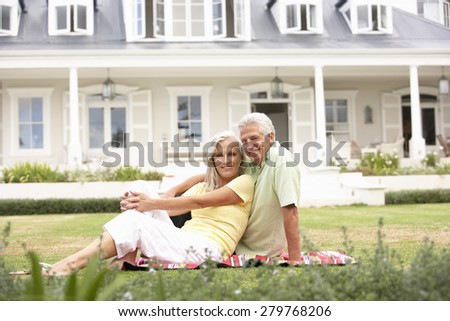 Grandparents And Grandchildren Sitting Outside House On Lawn