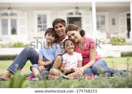 Family Sitting Outside House On Lawn