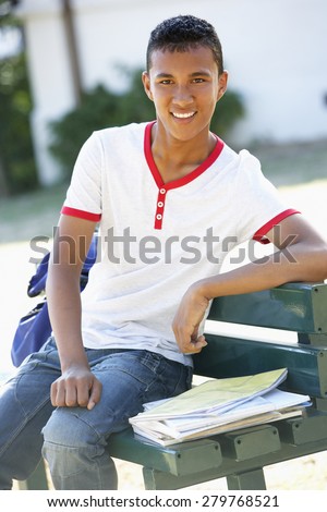 Male College Student Sitting On Bench With Backpack
