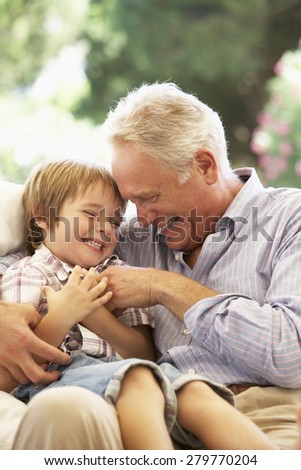 Grandfather With Grandson Laughing Together On Sofa