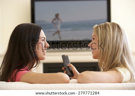 Two Women Watching Sad Movie On Widescreen TV At Home