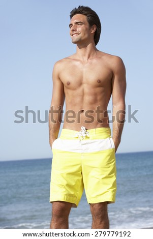 Young Man Wearing Swimming Costume Standing On Beach