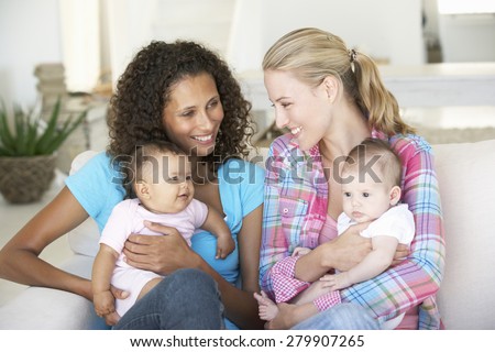 Two Young Mothers On Sofa At Home