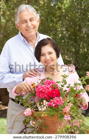 Senior Hispanic Couple Working In Garden Tidying Pots