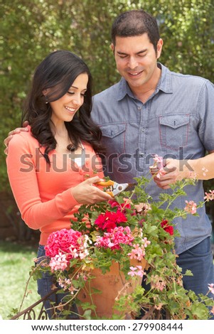 Hispanic Couple Working In Garden Tidying Pots