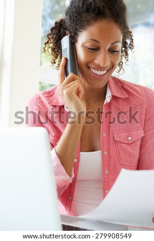 Young Woman On Phone Using Laptop At Home