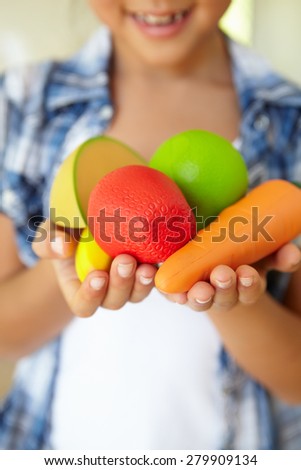 Young girl holding plastic fruit and vegetables