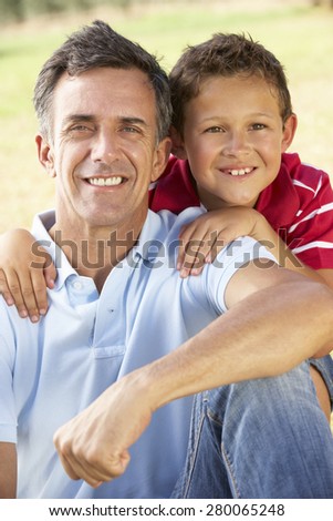 Middle Aged Father And Son Relaxing In Countryside
