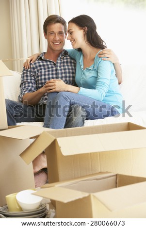 Young Couple Moving Into New Home Surrounded By Packing Boxes