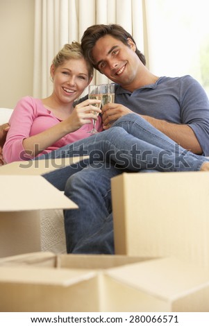 Young Couple Moving Into New Home Celebrating With Champagne