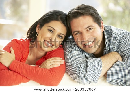 Hispanic Couple Relaxing At Home On Sofa