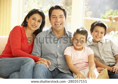Young Hispanic Family Relaxing On Sofa At Home