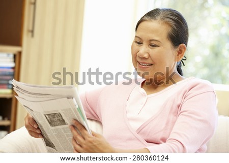 Senior Asian woman reading newspaper