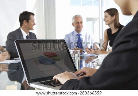 Close Up Of Businessman Using Laptop During Board Meeting Around Glass Table