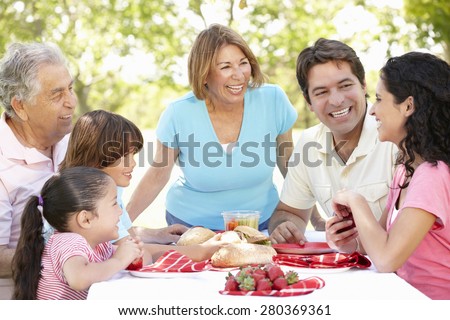 Three Generation Hispanic Couple Enjoying Picnic In Park