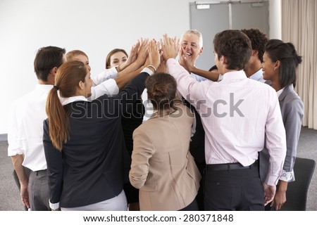 Group Of Businesspeople Joining Hands In Circle At Company Seminar
