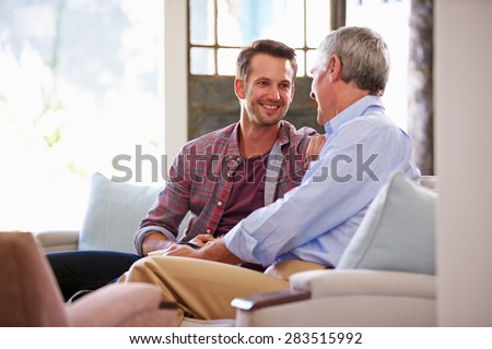 Senior Father With Adult Son Relaxing On Sofa At Home