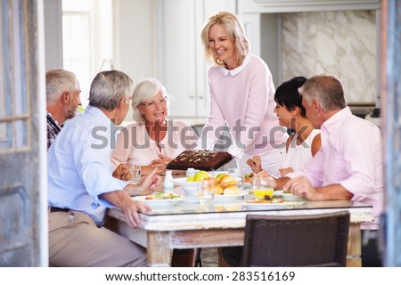 Woman Serving Cake To Group Of Friends Enjoying Meal At Home