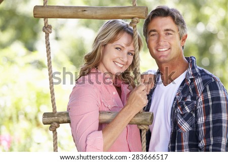 Middle Aged Couple In Garden By Treehouse