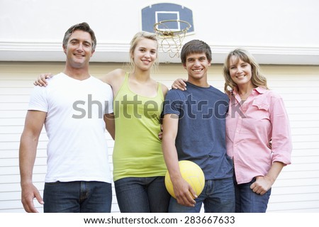 Portrait Of Teenage Family Playing Basketball Outside Garage