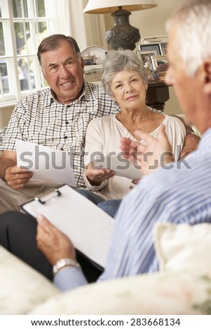 Retired Senior Couple Sitting On Sofa Talking To Financial Advisor