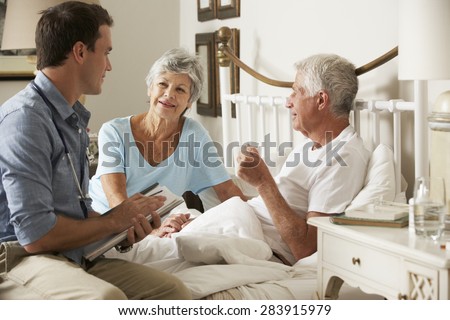 Doctor On Home Visit Discussing Health Of Senior Male Patient With Wife