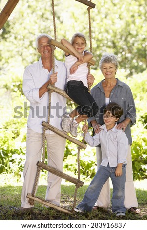 Grandchildren And Grandparents Standing By Tree House In Garden