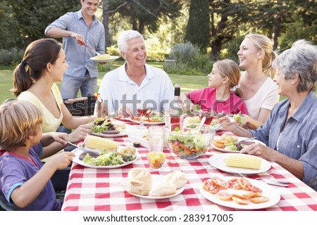 Three Generation Family Enjoying Barbeque In Garden Together