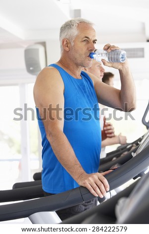 Man On Running Machine In Gym Drinking Water