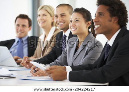 Group Of Business People Listening To Colleague Addressing Office Meeting