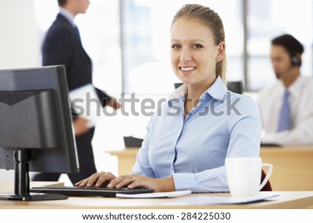 Businesswoman Working At Desk In Busy Office