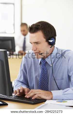 Friendly Service Agent Talking To Customer In Call Centre