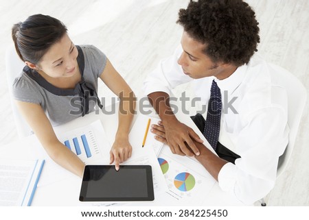 Overhead View Of Businesswoman And Businessman Working At Desk Together Using Digital Tablet