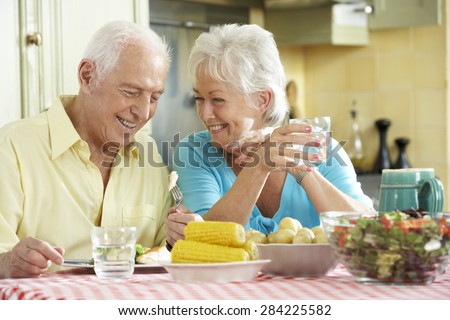 Senior Couple Eating Meal Together In Kitchen
