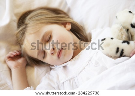 Young Girl Sleeping In Bed With Soft Toy