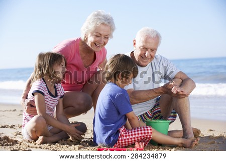 Grandparents And Grandchildren Building Sandcastle On Beach