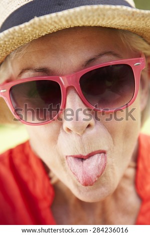 Head And Shoulders Portrait Of Senior Woman Poking Out Tongue