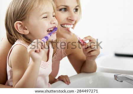 Mother And Daughter Brushing Teeth Together