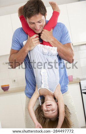 Father Holding Daughter Upside Down At Home