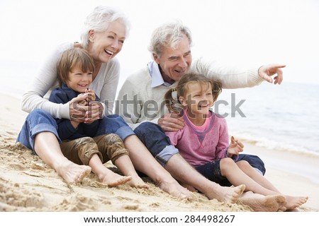 Grandparents And Grandchildren Sitting On Beach Together