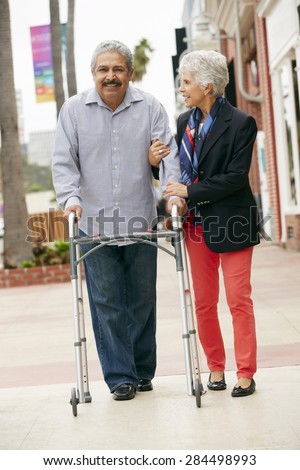 Wife Helping Senior Husband To Use Walking Frame