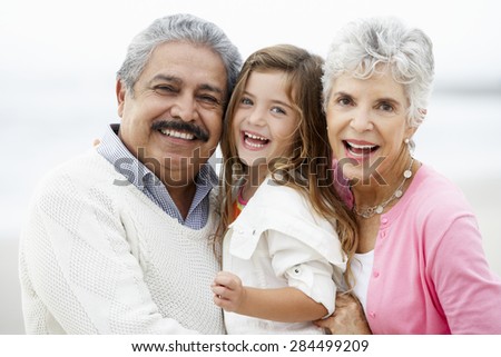 Portrait Of Grandparents On Beach With Granddaughter