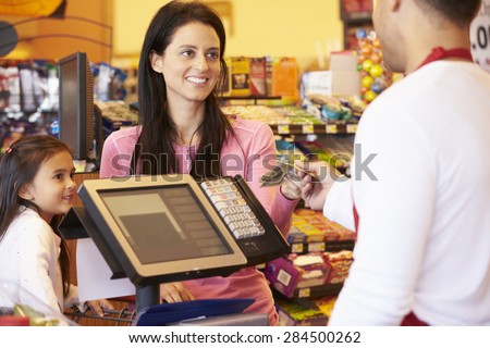Mother Paying For Family Shopping At Checkout With Card