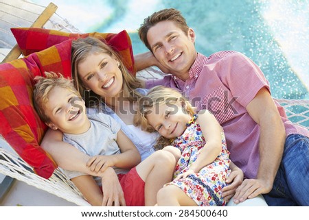 Family Relaxing In Garden Hammock Together